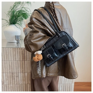 Détail d'un sac sous les aisselles vintage à carreaux avec tweed et breloque ours