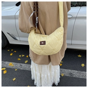 Détails du sac croissant jaune avec surpiqûres en cœur et étiquette à perles