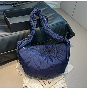 Detailed close-up of navy blue quilted dumpling bag with heart patterns and satin finish
