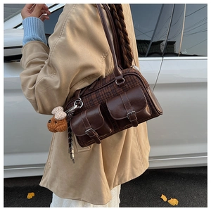 Détail d'un sac à bandoulière vintage à carreaux avec charm ours en peluche et boucles