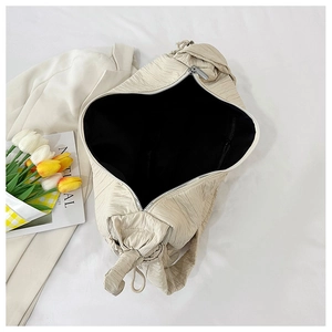 Close-up of beige pleated tote bag showing spacious interior with black fabric lining