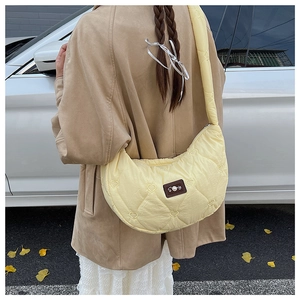 Détail du sac croissant en nylon jaune avec matelassage cœur et patch perle en extérieur