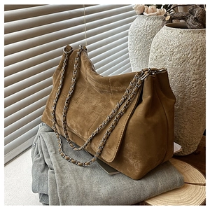 Détail d'un sac cabas en daim marron vintage avec bandoulière chaîne et motif surpiqué