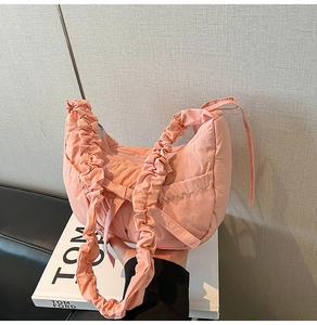 Détail du sac hobo rose plissé avec anse froncée et poche latérale sur fond moderne