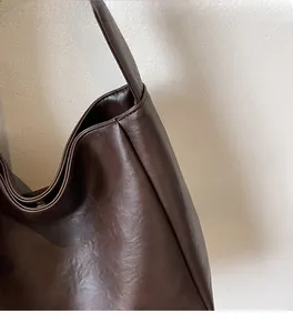 Détail du sac seau marron foncé montrant la texture du cuir PU et les plis souples