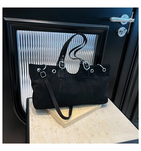 Detail view of black matte leather tote with silver buckle and adjustable straps