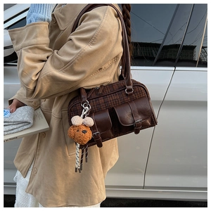 Detail of vintage brown houndstooth shoulder bag with buckle pockets and a bear charm