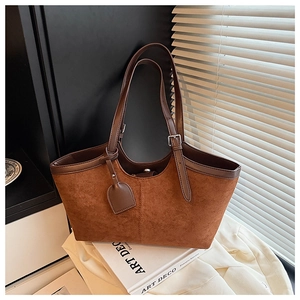 Detail view of brown suede tote bag with leather straps and silver adjustable metal buckles