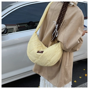 Détail du matelassage en forme de cœur et patch logo sur sac croissant en nylon jaune