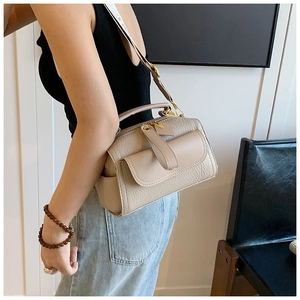 Dettaglio borsa a tracolla in pelle litchi beige con ampia tracolla e tasche laterali