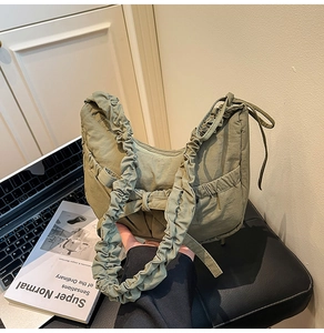 Détail de la bandoulière froncée et des lacets sur un sac croissant vert