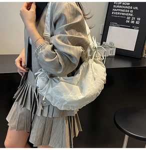 Detail view of the large white dumpling bag with drawstring folds on a fashion model