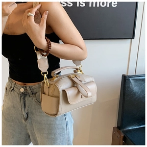 Borsa Boston beige in pelle martellata con tracolla intrecciata indossata da una modella
