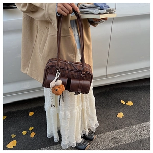 Détail du sac polochon rétro à carreaux avec poches avant et breloque ours en peluche