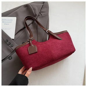 Close-up of burgundy suede tote bag with brown leather straps and silver buckle detail