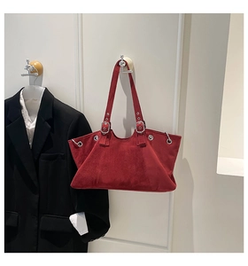 Detail of red suede tote bag with silver metal eyelets and adjustable shoulder strap