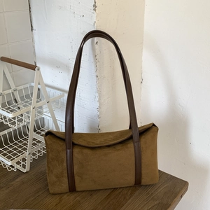 Detailed view of a vintage brown suede pillow bag on a wooden surface in home setting