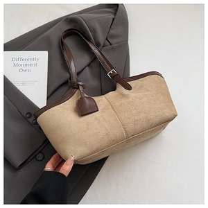 Detail of suede tote bag with brown leather trim and adjustable metallic shoulder strap