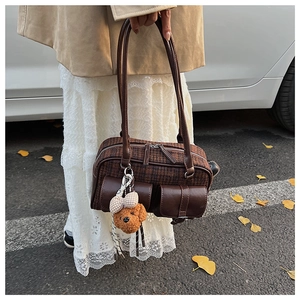 Détail du sac à carreaux vintage avec breloque ours en peluche et feuilles d'automne