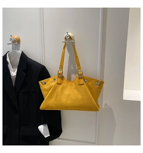 Detail of bright yellow tote bag showing trapezoidal structure and silver metal eyelets