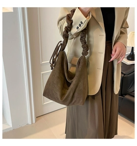 Detail of a dark coffee brown suede hobo bag featuring a decorative pleated shoulder strap