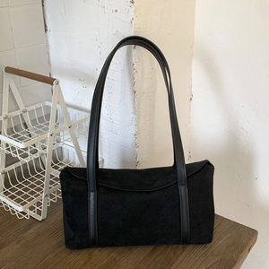 Detail of vintage black suede hobo bag with smooth leather strap on a wooden table