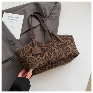 Detail of leopard print tote bag with brown adjustable handle and shield pendant