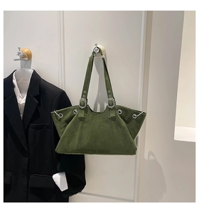 Detail of dark green suede tote bag with large silver eyelets and adjustable strap