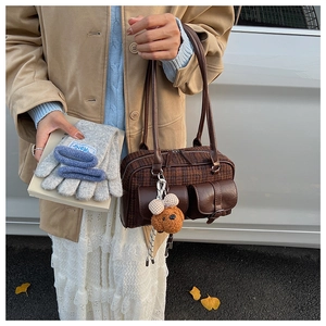 Close-up of brown plaid bowling bag featuring leather trim and a cute plush dog charm