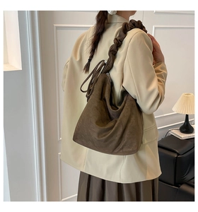 Detail of dark brown suede crescent tote bag with elegant pleated shoulder strap