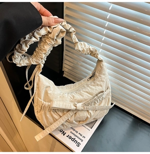 Détail du sac hobo plissé beige avec grand nœud décoratif et bandoulière texturée