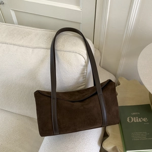Macro detail of deep brown suede texture and leather straps on retro pillow bag