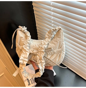 Gros plan du sac croissant plissé beige avec nœud décoratif et bandoulière froncée