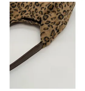Gros plan sur le tissu peluche léopard et la bandoulière en cuir marron avec couture