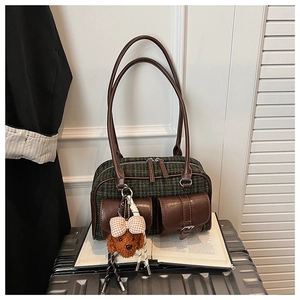 Détail d'un sac à carreaux vintage avec bordures en cuir et pendentif chien en peluche
