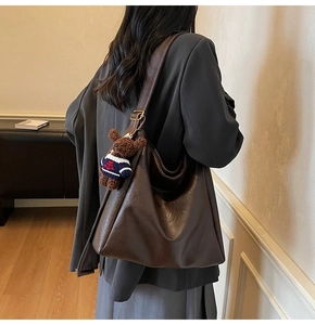 Détail du sac seau marron foncé en suédine avec bandoulière réglable et breloque ours