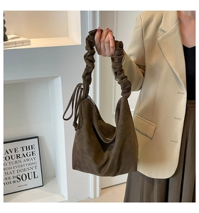 Detailed view of dark brown faux suede tote bag with ruched handle and side tassels