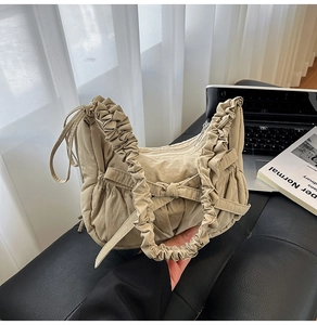 Détail d'un sac bandoulière beige plissé avec nœud déco et bandoulière à volants