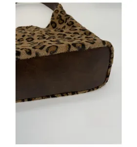 Détail du fond renforcé du sac cabas léopard en peluche avec une base en cuir marron