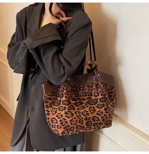 Detail of leopard print tote bag featuring brown leather trim and thin shoulder strap