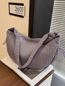 Light purple pleated shoulder bag with drawstring detail on a cozy home background