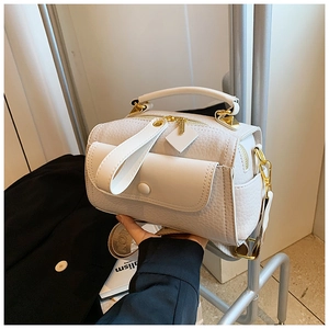 Dettaglio borsa bianca in pelle martellata con finiture dorate e tracolla tessuta