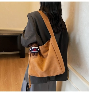 Gros plan du sac seau en daim marron avec un charmant pendentif ours en peluche sur la bandoulière