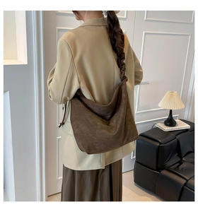 Detail of a large dark brown tote bag featuring a unique pleated ruched shoulder strap design
