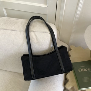 Minimalist black suede pillow bag shown on a sofa with natural lighting and soft textures