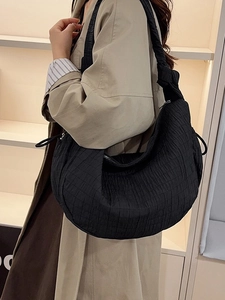 Minimalist black pleated crescent hobo bag with quilted texture and shoulder strap
