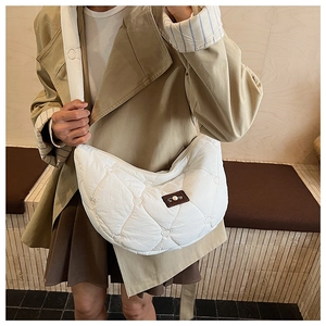 Détail du sac bandoulière blanc avec matelassage en cœurs et étiquette décorative marron