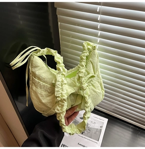 Détail du sac à main vert plissé avec anses froncées dans un décor élégant