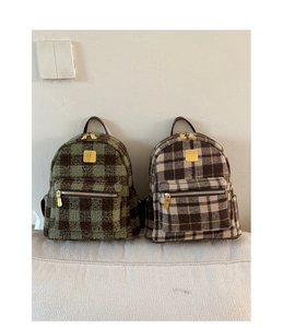 Detailed view of checkered wool texture on backpacks with golden metal zippers