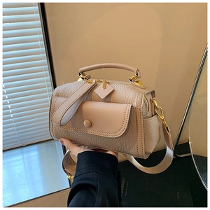 Dettaglio borsa in pelle martellata con hardware dorato e tracolla larga morbida